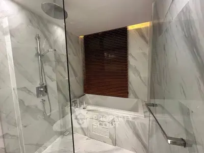 Luxurious marble bathroom with glass shower and modern bathtub.
