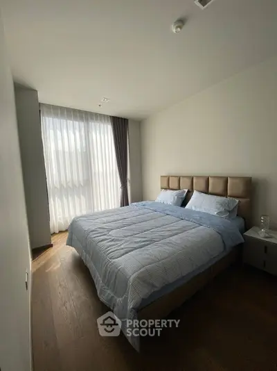 Cozy bedroom with large window and elegant curtains, featuring a comfortable double bed.