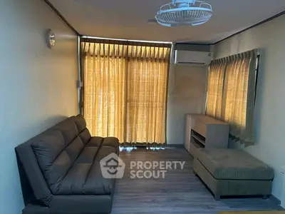 Cozy living room with modern sofa and natural light through large windows.