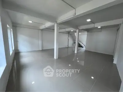 Spacious open-plan interior with sleek tiled flooring and modern lighting, ideal for versatile use.