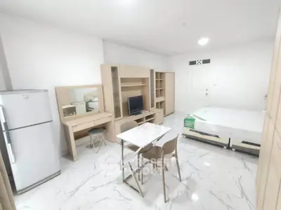 Modern studio apartment with sleek furniture and marble flooring, featuring a compact dining area and ample storage.