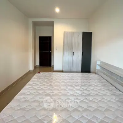Spacious bedroom with modern wardrobe and comfortable mattress in a well-lit apartment.