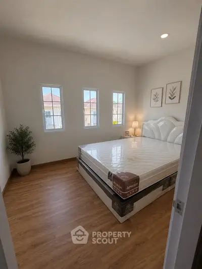 Bright and cozy bedroom with large windows and modern decor, perfect for relaxation.