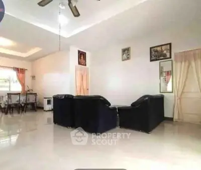 Spacious living room with elegant black sofas and dining area, perfect for family gatherings.