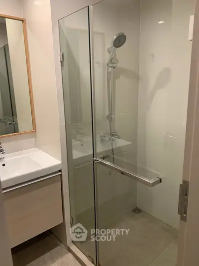 Modern bathroom with glass shower enclosure and sleek vanity in a contemporary apartment.