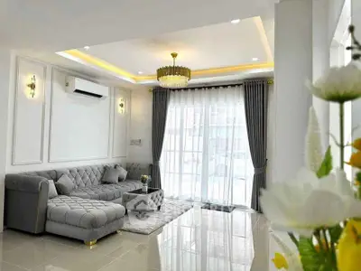 Elegant living room with luxurious sofa and chandelier, featuring large windows and modern decor.