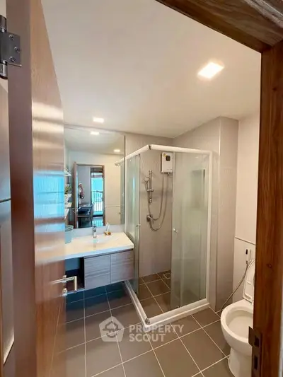 Modern bathroom with glass shower and sleek fixtures in contemporary home.