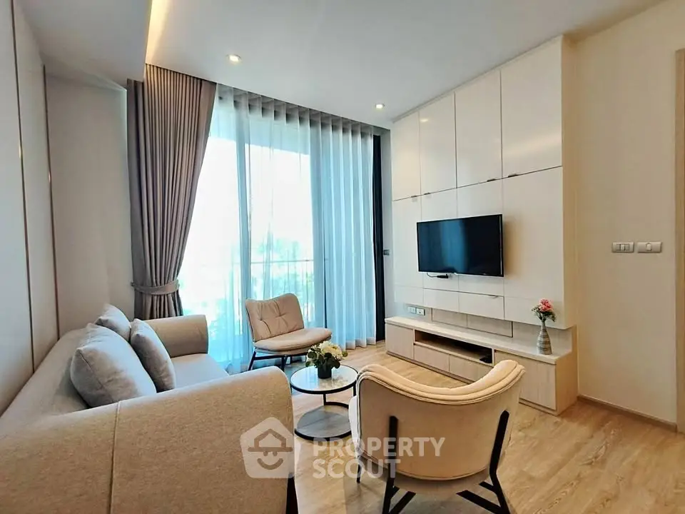 Modern living room with elegant furniture and large window offering natural light.