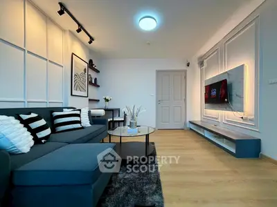 Modern living room with stylish decor and wall-mounted TV, featuring a cozy sofa and elegant lighting.