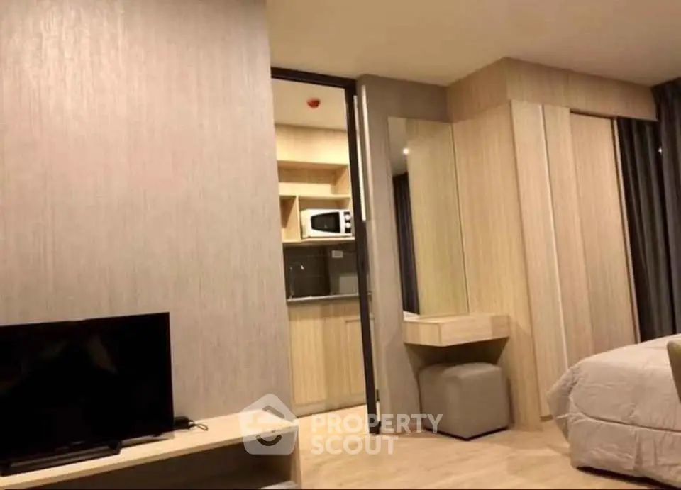 Modern studio apartment with open kitchen and cozy living area, featuring sleek wooden finishes and contemporary design.