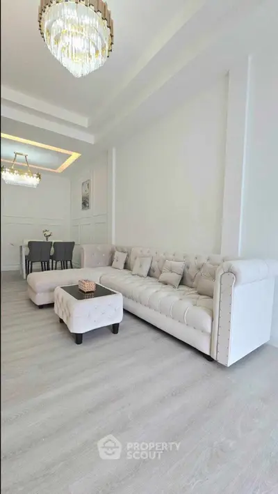 Luxurious living room with elegant white sofa and modern chandelier lighting.