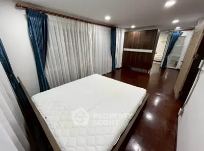 Spacious bedroom with elegant curtains and hardwood flooring