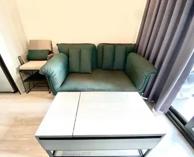 Modern living room with stylish green sofa and sleek coffee table near large window.