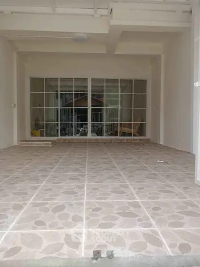 Spacious tiled patio with sliding glass doors leading to interior space, ideal for outdoor relaxation.