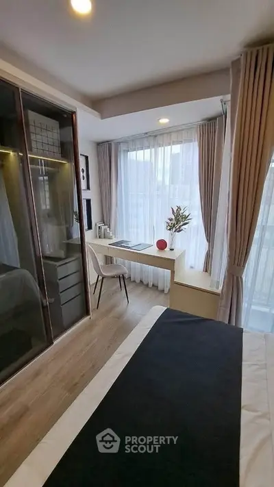 Modern bedroom with stylish decor and natural light, featuring a cozy workspace by the window.