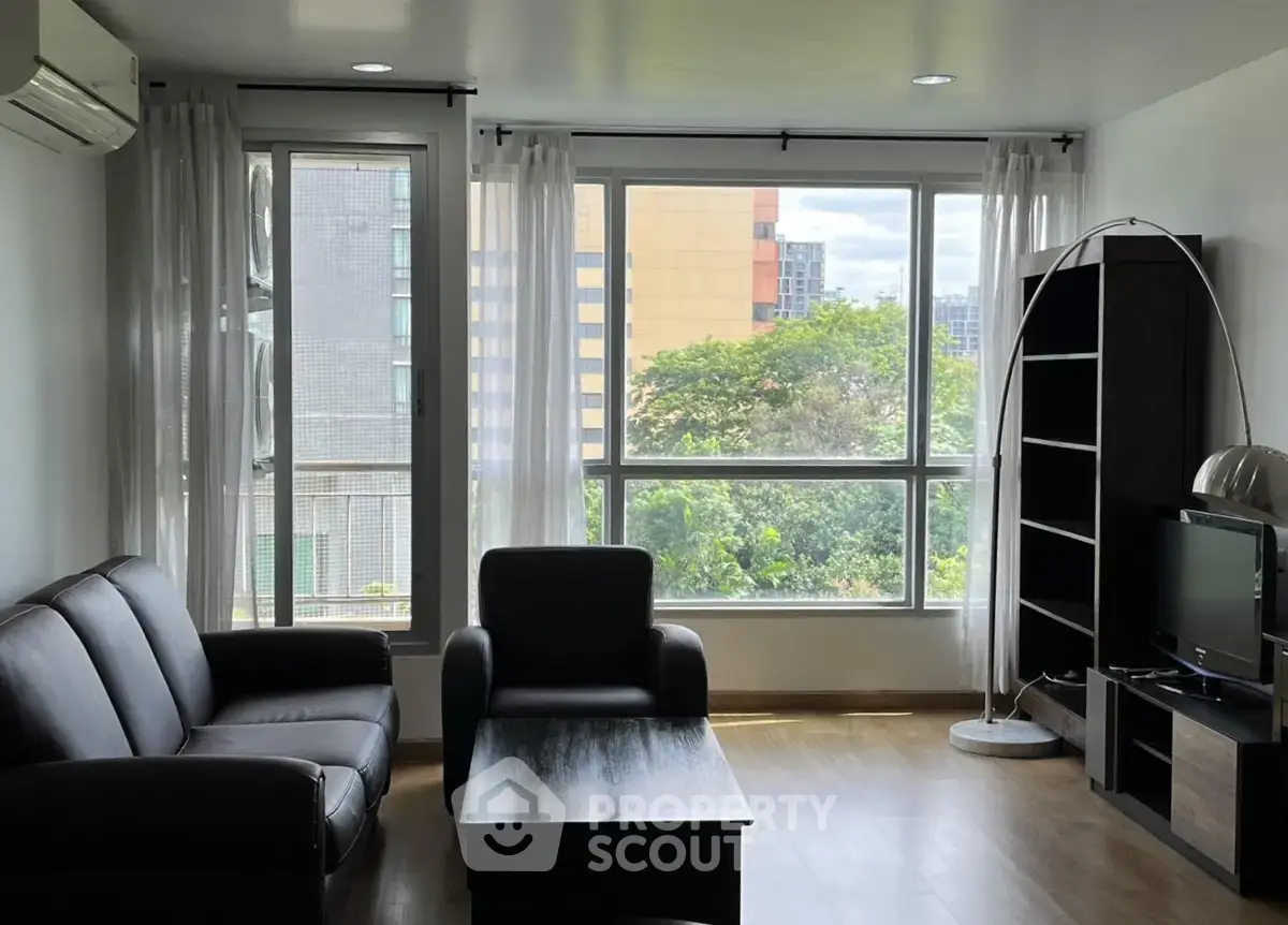 Spacious living room with large windows and modern furniture, offering a bright and inviting atmosphere.