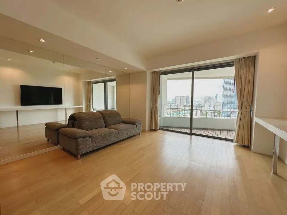 Spacious living room with large balcony and city view, featuring modern decor and ample natural light.