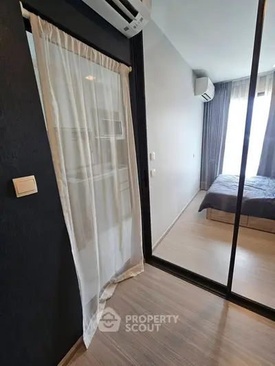 Modern bedroom with glass partition and air conditioning, featuring sleek design and natural light.