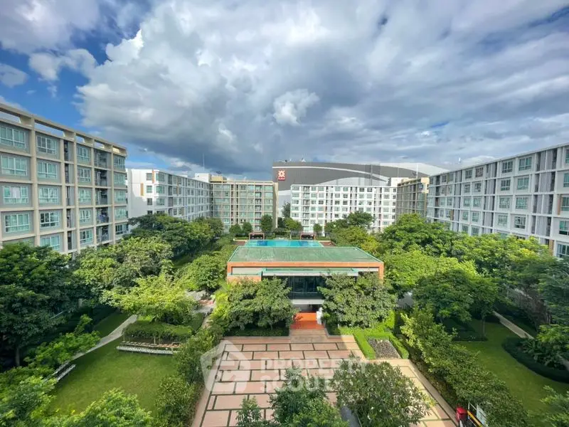 Stunning aerial view of modern apartment complex with lush green gardens and spacious courtyard.