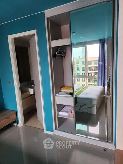 Modern bedroom with mirrored closet and ensuite bathroom in a stylish apartment.