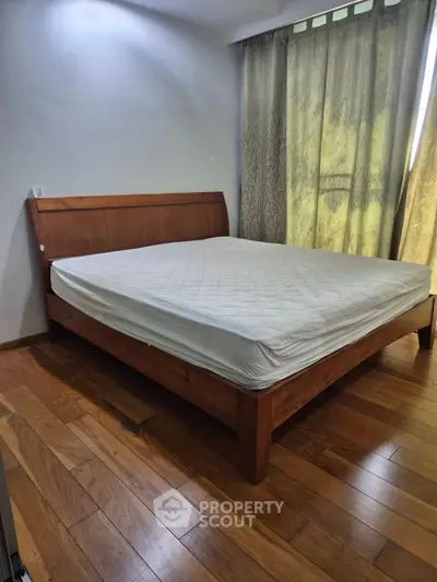 Spacious bedroom with wooden flooring and large bed, perfect for comfort and relaxation.