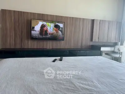 Modern bedroom with wall-mounted TV and sleek wooden paneling.