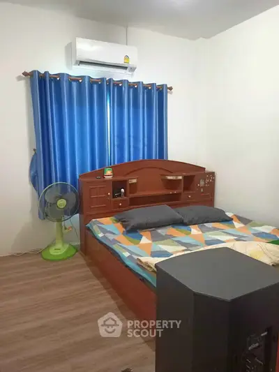 Cozy bedroom with wooden bed, vibrant blue curtains, and air conditioning for comfort.