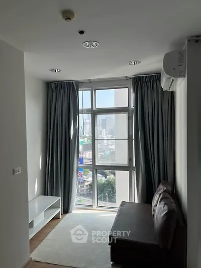 Cozy living room with large window offering city view, modern furniture, and natural light.