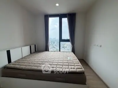 Modern bedroom with large window offering stunning city view.