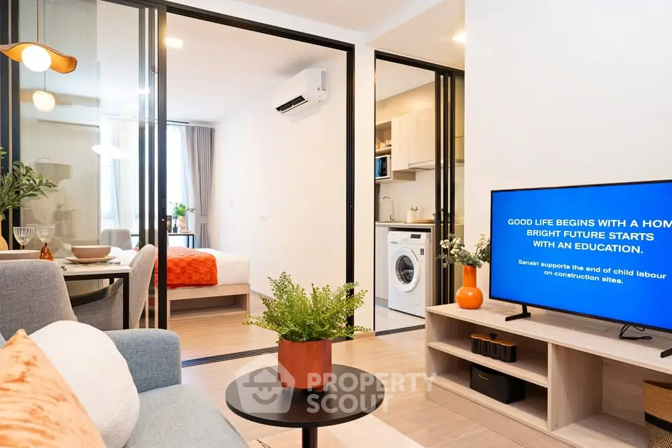 Modern open-plan living room with kitchen and bedroom, featuring stylish decor and natural light.