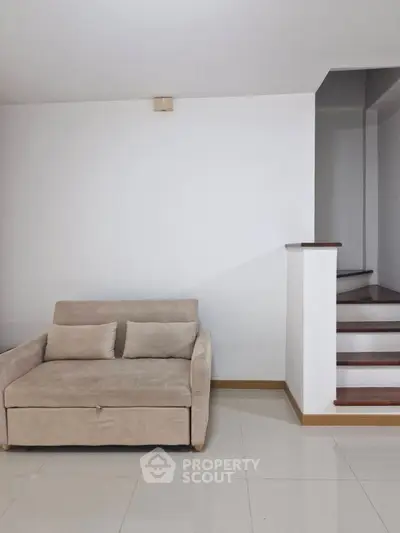 Modern minimalist living room with cozy beige sofa and sleek staircase