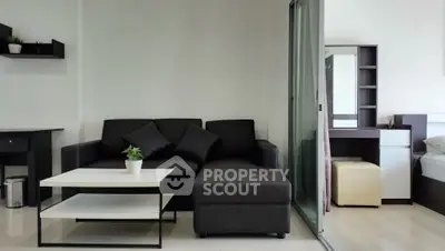 Modern living room with sleek black sofa and white coffee table in stylish apartment.