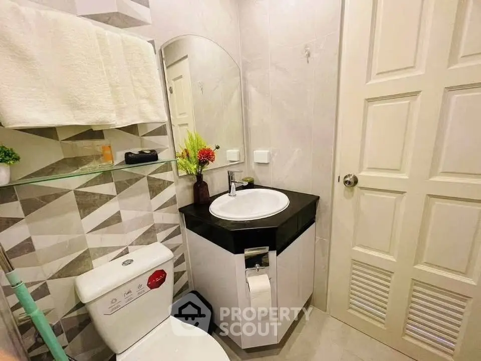 Modern bathroom with geometric tiles and sleek fixtures in a stylish home.