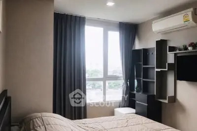 Cozy bedroom with modern decor and large window offering natural light and city view.