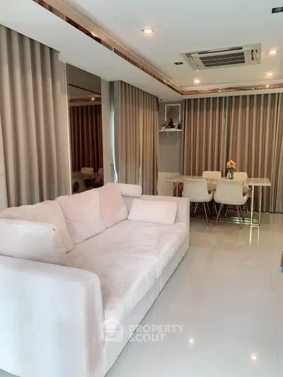 Spacious living room with elegant dining area and plush sofa, featuring modern decor and ample natural light.
