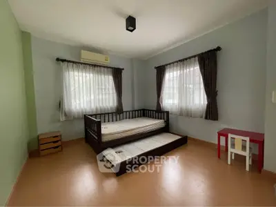 Spacious bedroom with twin beds and natural light, perfect for a cozy retreat.