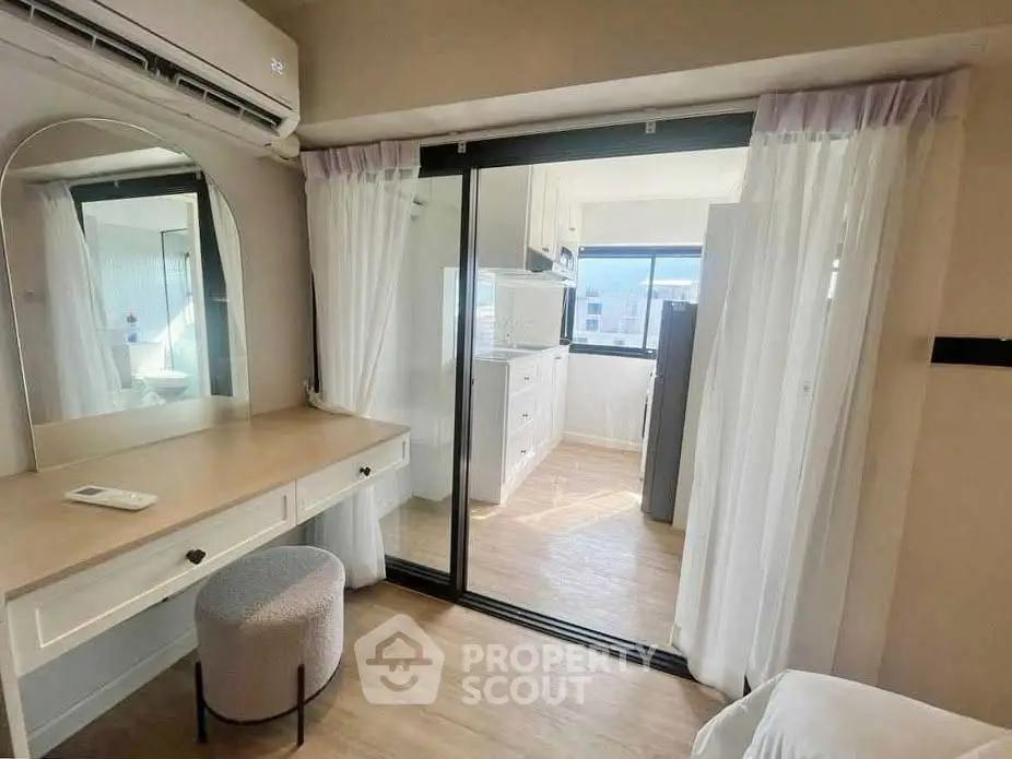 Bright and airy bedroom with sliding glass doors leading to a modern kitchen, featuring elegant decor and natural light.