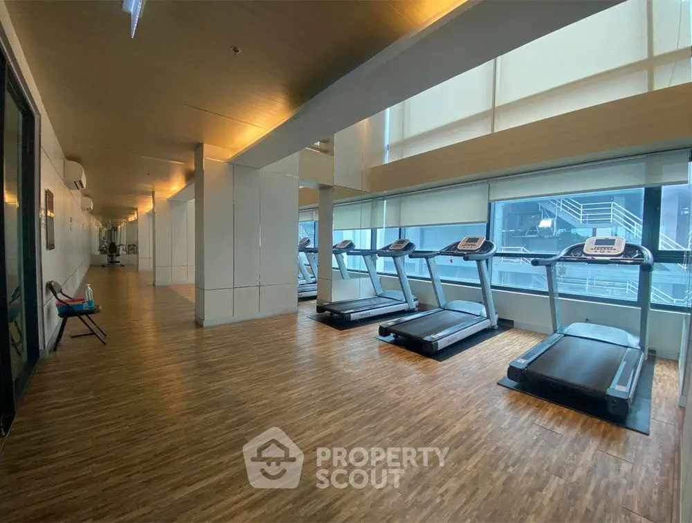 Modern gym with treadmills and wooden flooring in a high-rise building
