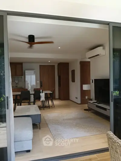 Modern open-plan living room with stylish furniture and large sliding glass doors.