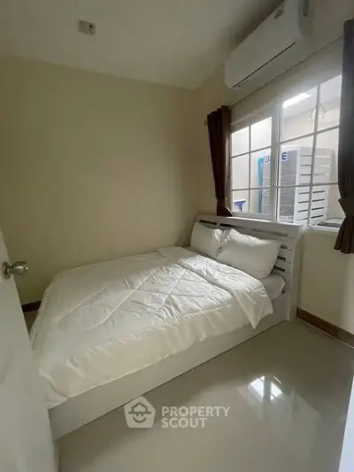 Cozy bedroom with modern air conditioning and natural light from window.
