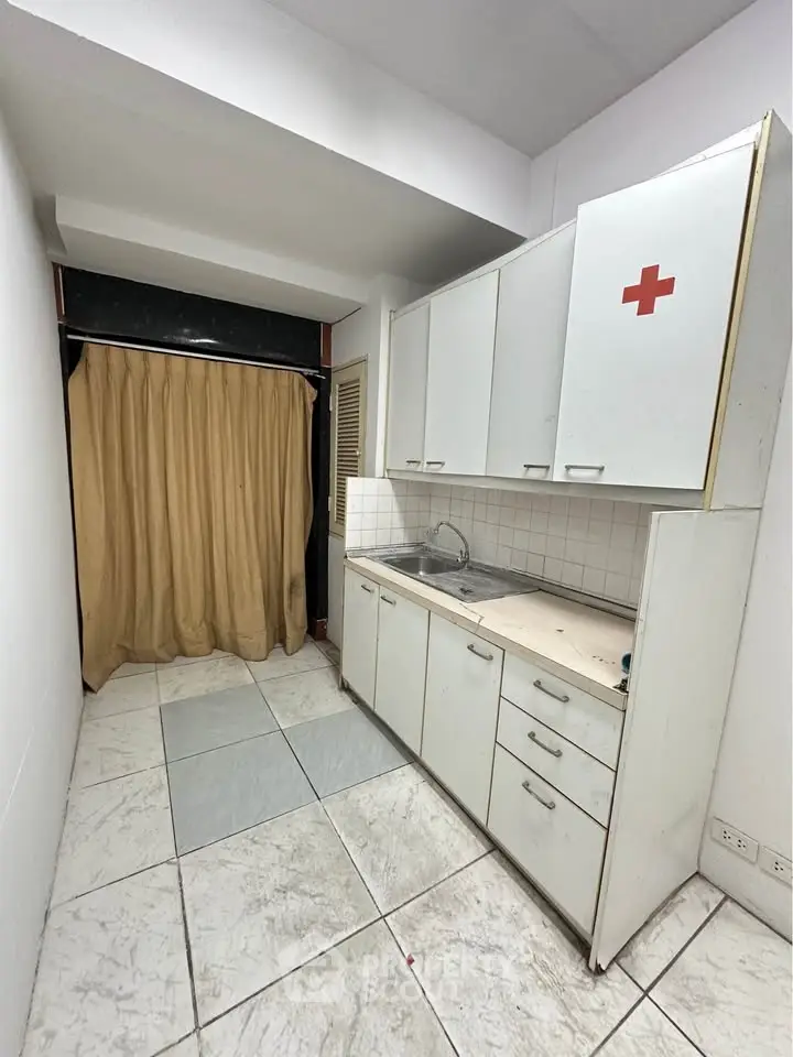Compact kitchen with white cabinets and tiled floor, featuring a minimalist design.