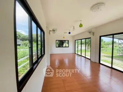 Spacious sunlit room with large windows and garden view, perfect for versatile living space.