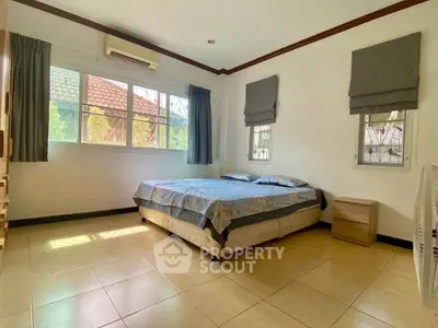 Spacious bedroom with large windows and natural light, featuring a comfortable bed and modern decor.