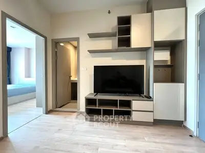 Modern living room with sleek TV unit and open doorway to bedroom