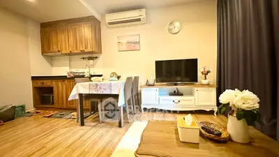 Cozy living room with wooden flooring, compact kitchen, and stylish decor
