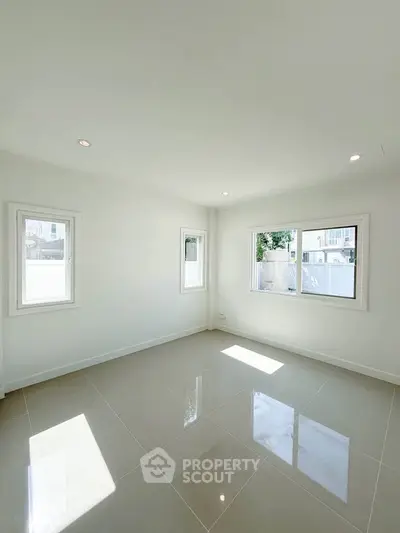 Bright and spacious empty room with large windows and glossy tiled floor, perfect for customization.