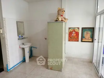 Simple bathroom with sink, mirror, and storage cabinet, featuring tiled floor and wall decor.