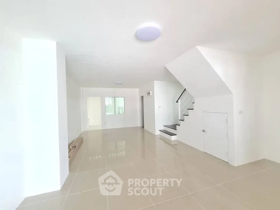 Spacious modern living room with sleek tile flooring and staircase