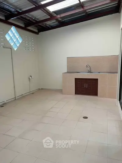 Spacious tiled utility area with sink and covered roof, ideal for laundry or storage.