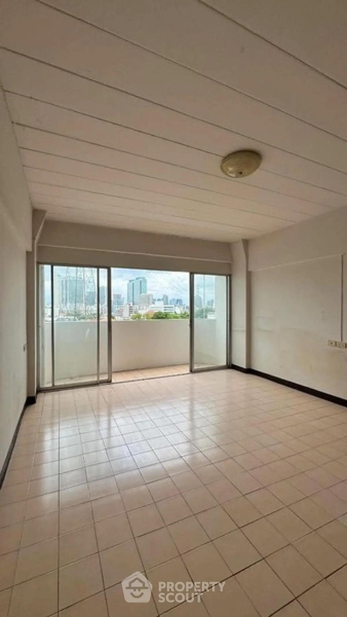 Spacious living room with large windows offering a stunning city view, perfect for urban living.